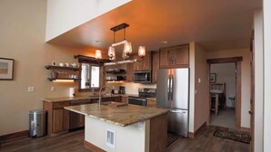 A modern kitchen with a central island, stainless steel appliances, and wooden cabinetry. - Your Own Private Idaho for Summer Mountain Retreat (New Meadows)