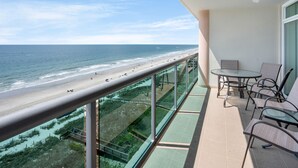 Varanda com guarda-corpo de vidro com vista para uma praia e oceano.