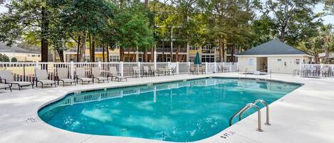 A rectangular pool with a white deck and a white fence surrounding it.