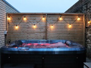 Un bain à remous avec un décor en bois et des guirlandes lumineuses.