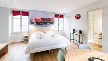 A modern hotel room with a large bed, a desk, and a shower area.