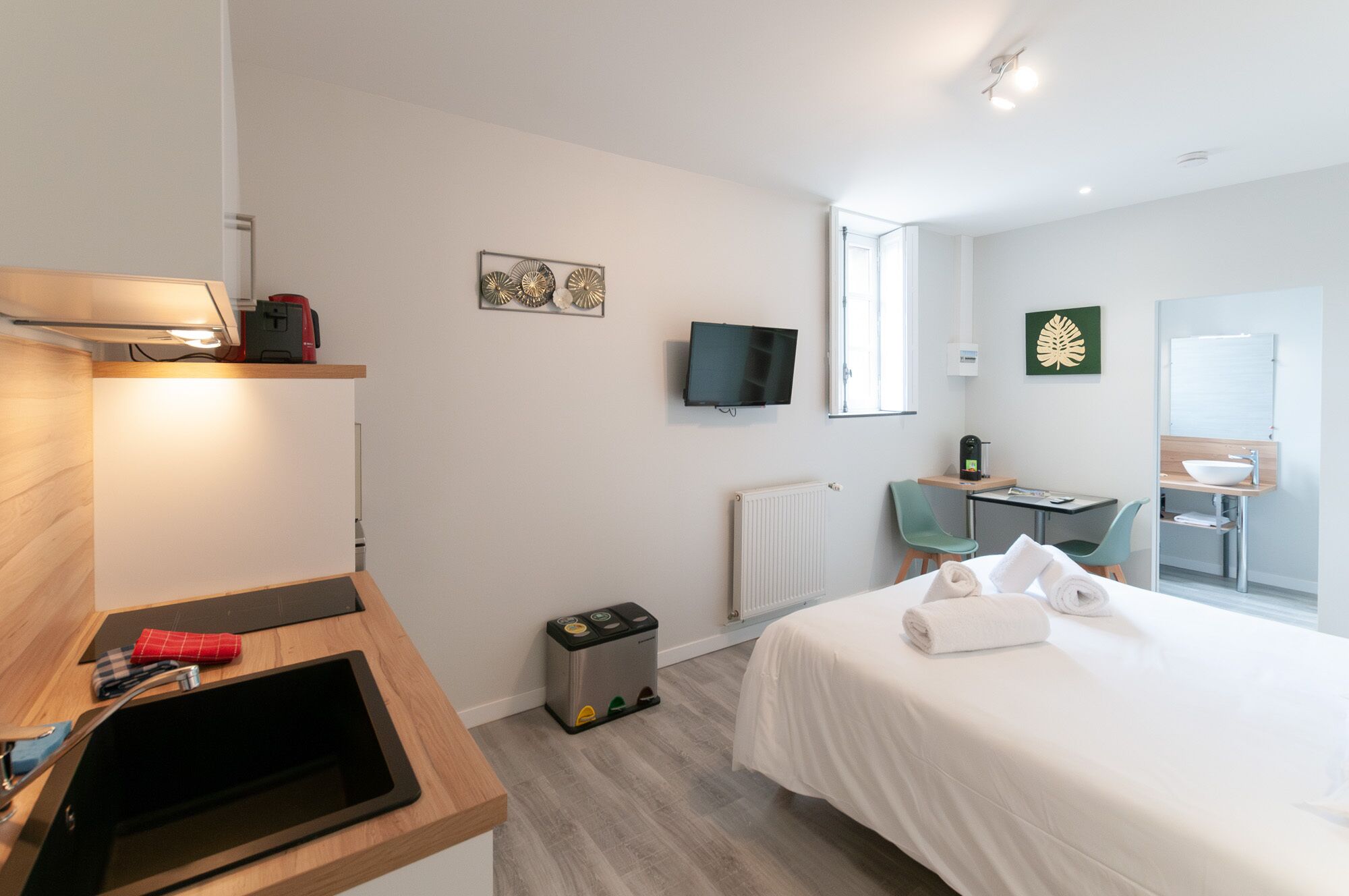 Habitación de hotel con cama, escritorio, televisor, radiador y ventana.