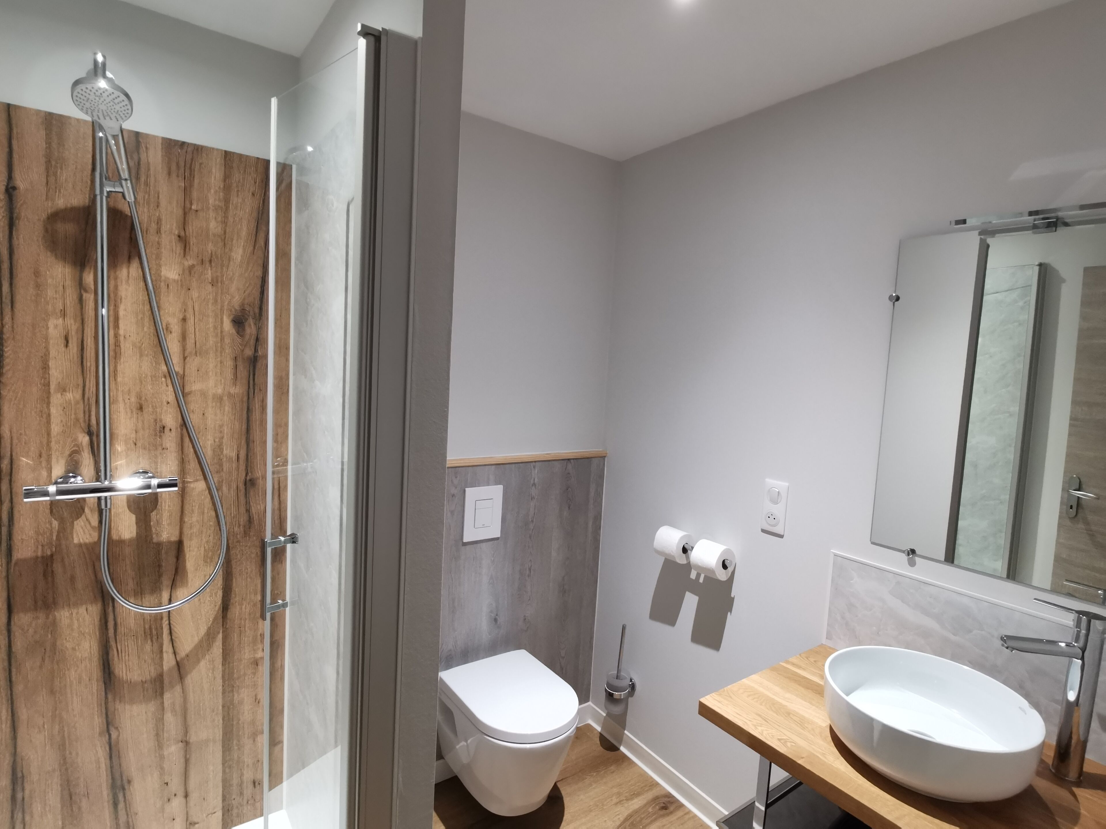 Une salle de bain moderne avec une douche à parois de verre, des toilettes et un meuble-lavabo doté d’un grand évier et d’un miroir.
