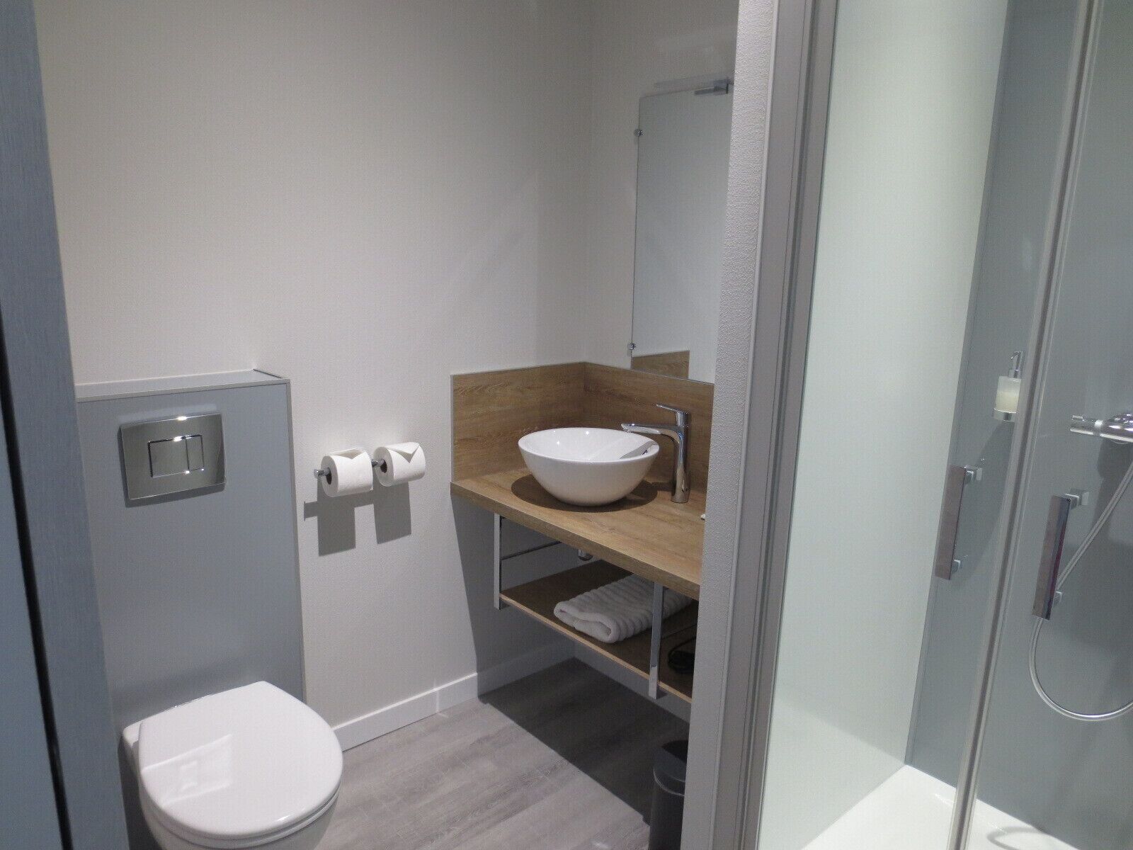 Une salle de bain moderne équipée de toilettes, d’un lavabo et d’une douche.