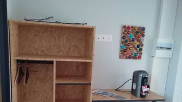 Ein Zimmer mit einem Holzschrank, einem kleinen Tisch mit Kaffeemaschine und einer Wandsteckdose.