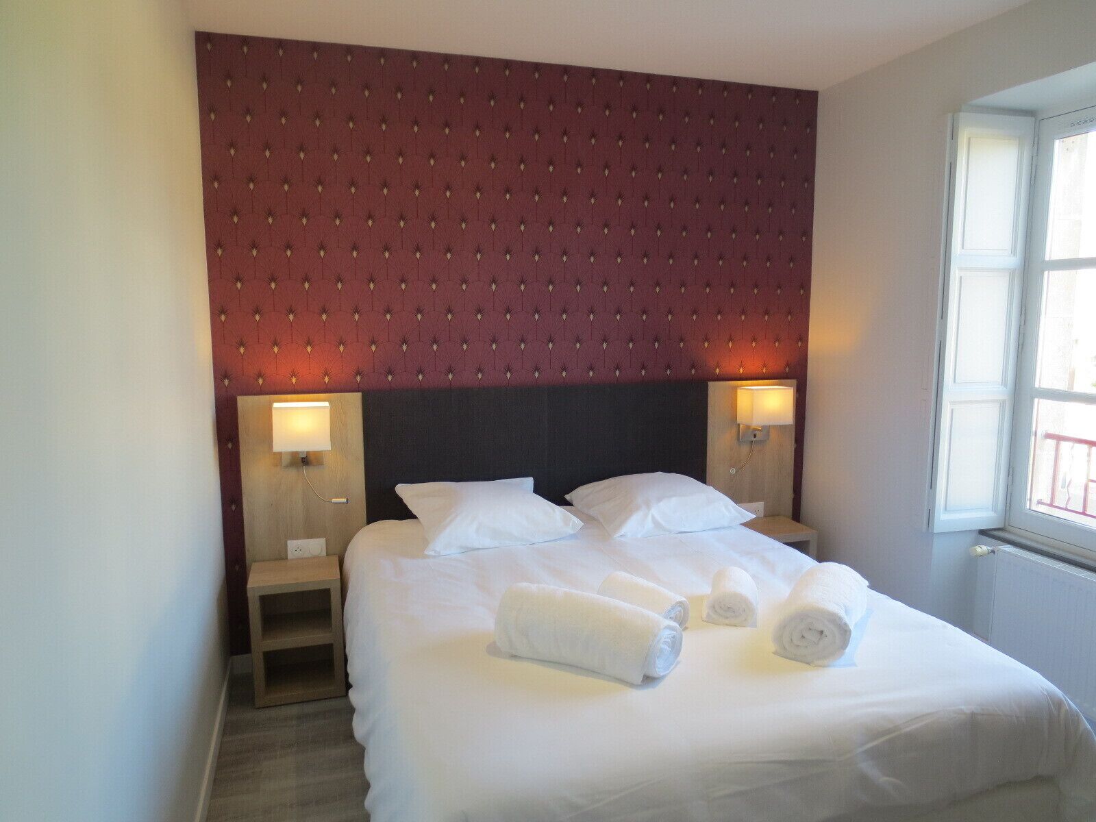 Une chambre d’hôtel avec un grand lit, deux tables de chevet et une fenêtre donnant sur un beau paysage.