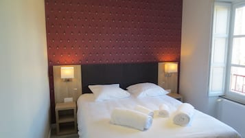 A hotel room with a large bed, two bedside tables, and a window with a view.