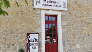 A stone building with a red door and a sign for Malicorn's Appart-Hotel. - Malicorn' Appart-hôtel (Malicorne-sur-Sarthe)