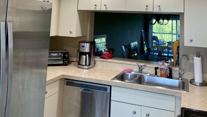 Une cuisine moderne équipée d’appareils électroménagers en acier inoxydable, d’un lave-vaisselle et d’une machine à café.