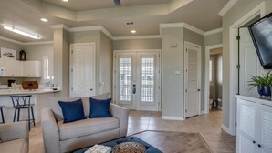 A spacious living area with a beige sofa, a coffee table, and a TV mounted on the wall. - Chic 1BR/1BA Retreat with Serene Balcony Views and Golf Cart at Sandestin Golf and Beach Resort! (Miramar Beach)