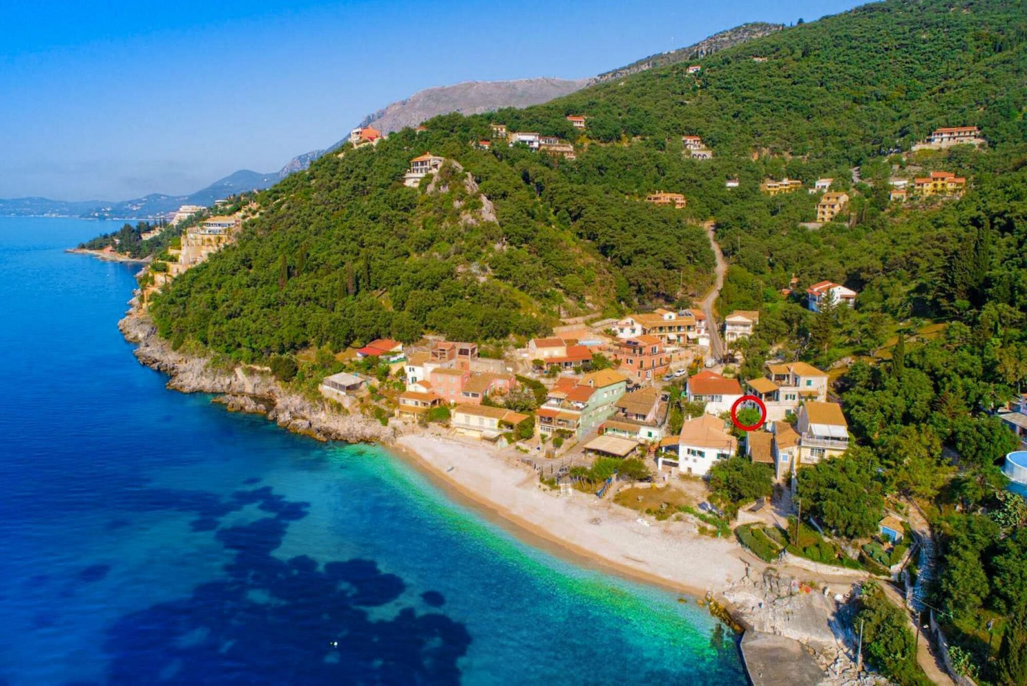Un villaggio costiero con case su una collina che si affaccia su una spiaggia.