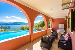 A balcony with a pool, outdoor furniture, and a view of the sea and mountains. - Bougainvillea Large Private Pool Walk to Beach Sea Views A C Wifi Car Not Required Eco-friend - 195 (Corfu)