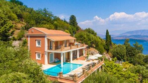 A two-story house with a swimming pool, surrounded by greenery and overlooking a body of water. - Villa Emilios Large Private Pool Sea Views A C Wifi - 217 (Corfu)