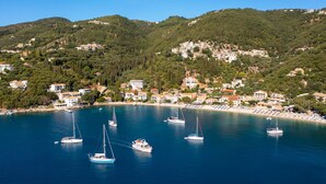 A coastal town with buildings on hills, a beach, and several sailboats in the water. - Villa Emilios Large Private Pool Sea Views A C Wifi - 217 (Corfu)