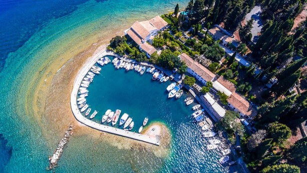 An aerial view of a coastal property with a marina, surrounded by dense greenery and a clear blue sea. - Dinos Walk to Beach Sea Views A C Wifi Car Not Required - 291 (Corfu)