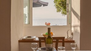 A dining table with a bottle of Moschofilero white wine, glasses, and a view of the sea through a window. - Dinos Walk to Beach Sea Views A C Wifi Car Not Required - 291 (Corfu)