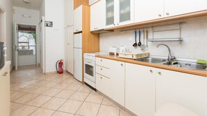 Een kleine keuken met witte kastjes, een houten aanrecht, een spoelbak en een brandblusser.