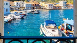 A coastal town with a marina filled with boats, surrounded by colorful buildings and clear blue waters. - Spiros Jetty House Walk to Beach Sea Views A C Car Not Required - 302 (Paxos)