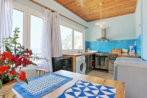 A compact kitchen with a washing machine, a stove, and a sink.