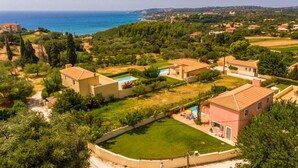A residential area with houses, a swimming pool, and a view of the sea. - Villa Vali Large Private Pool Walk to Beach Sea Views A C Wifi Car Not Required - 1019 (Kefalonia)