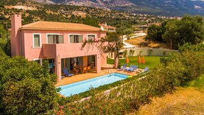 A pink villa with a swimming pool, outdoor seating, and a view of mountains. - Villa Vali Large Private Pool Walk to Beach Sea Views A C Wifi Car Not Required - 1019 (Kefalonia)