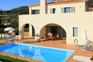A two-story building with a swimming pool, outdoor seating, and a view of the surrounding landscape. - Villa Katerina Large Private Pool Walk to Beach Sea Views A C Wifi Car Not Required - 1021 (Kefalonia)