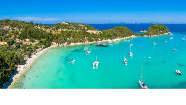 Vista aérea de una zona costera con playa, barcos y edificios.