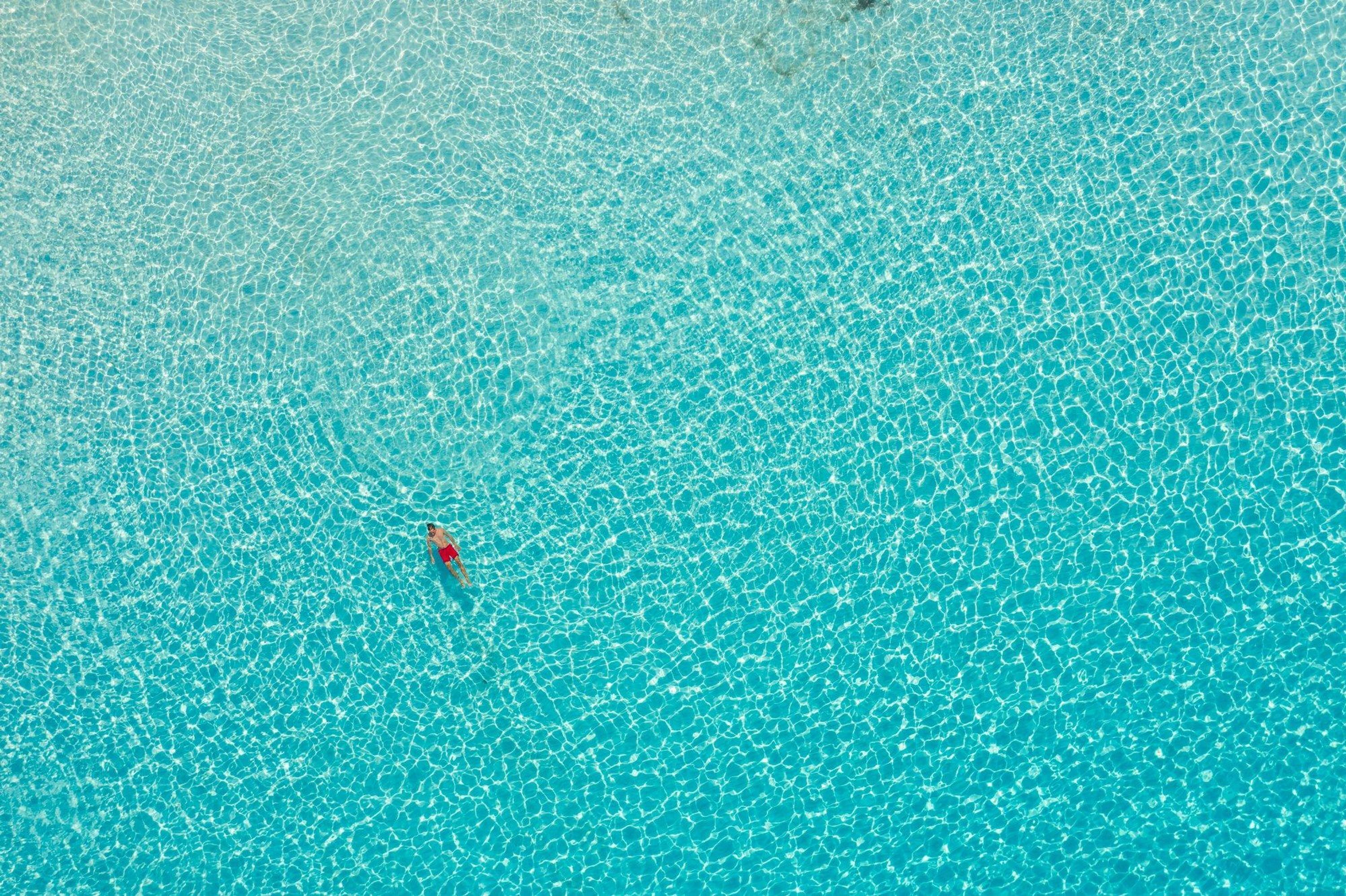 Une piscine d’un bleu éclatant où une personne porte un maillot de bain rouge.