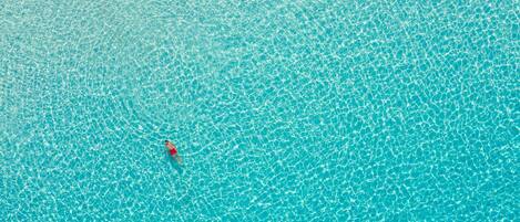 Une piscine d’un bleu éclatant où une personne porte un maillot de bain rouge.