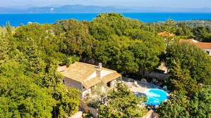 Una villa con piscina rodeada de vegetación exuberante y vista al mar.