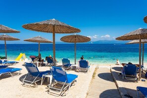 En strand med solstolar, parasoller och en strandpromenad av trä.