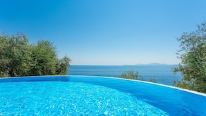 A clear blue swimming pool with a view of the sea and distant mountains. - Villa Petros Large Private Pool Walk to Beach Sea Views A C Wifi Car Not Required - 180 (Corfu)