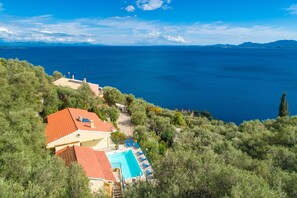 A coastal property with a swimming pool, a red-roofed building, and a view of the sea.