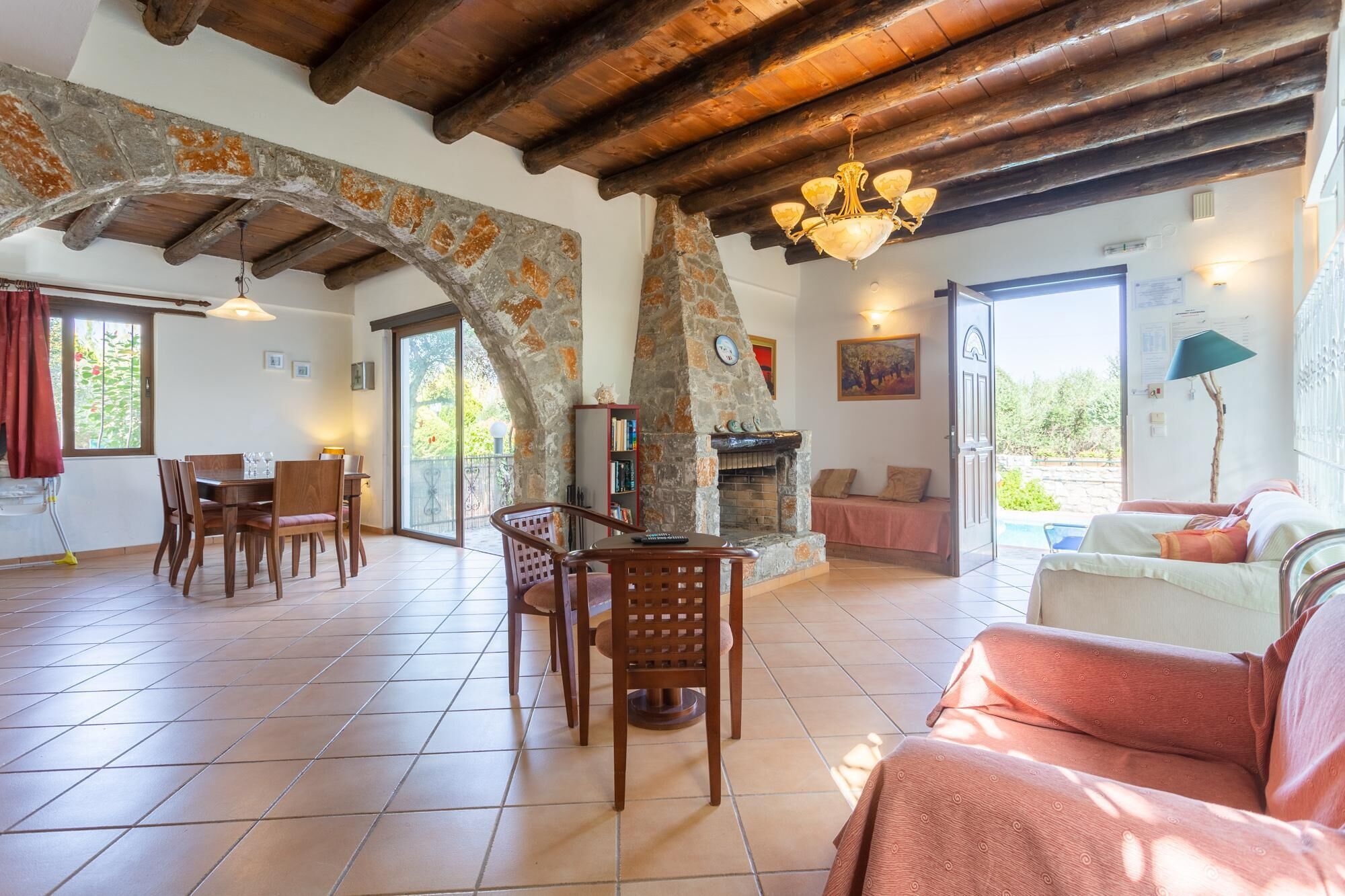 A spacious living area with a stone fireplace, wooden furniture, and a balcony with a view.