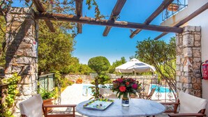 Un patio exterior con paredes de piedra, una piscina y una mesa con sillas.