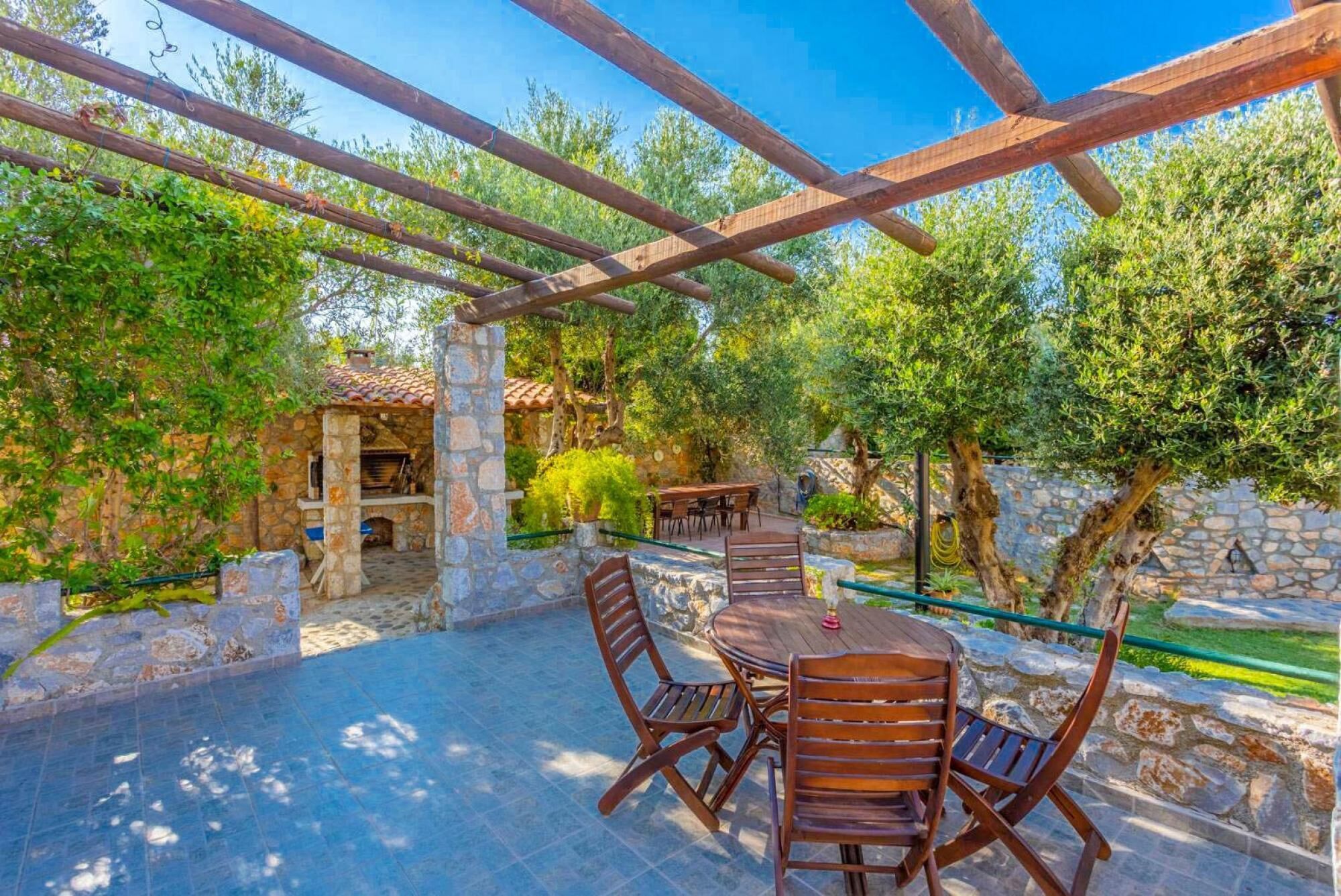 Un patio al aire libre con piso de piedra, mobiliario de madera y pared de piedra.