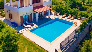 Ein zweistöckiges Haus mit Swimmingpool, Sitzgelegenheiten im Freien und einem Garten.