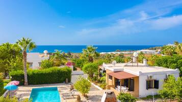 Zona residencial com piscina, edifícios brancos e vista para o mar.