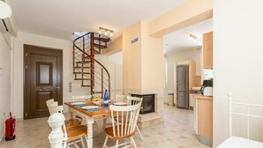 A dining area with a wooden table and chairs, a spiral staircase, a fireplace, and a kitchen area with cabinets and appliances. - Villa Fedra Large Private Pool Walk to Beach A C Wifi Car Not Required Eco-friendly - 1878 (Kefalonia)