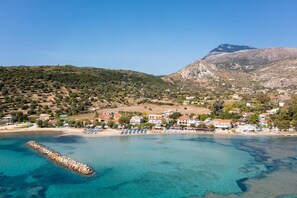 Une ville côtière dotée d’une plage, d’eaux d’un bleu limpide et, en arrière-plan, d’une montagne rocheuse.