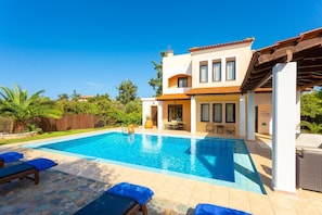A two-story house with a swimming pool, outdoor seating, and a pergola.
