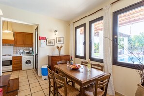A compact kitchen with a dining area, a washing machine, and a small trash bin.