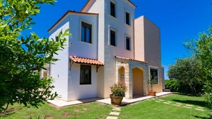A two-story house with a tiled roof, a front entrance with a door, and a small garden area with a potted plant. - Villa Kefalas Large Private Pool A C Wifi - 1921 (Apokoronas)