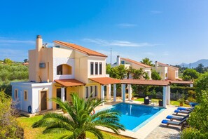 A modern villa with a swimming pool, multiple balconies, and a lush garden.
