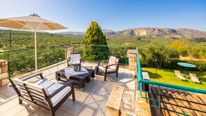 Une terrasse aménagée avec du mobilier d’extérieur, une table et une vue sur un paysage montagneux.