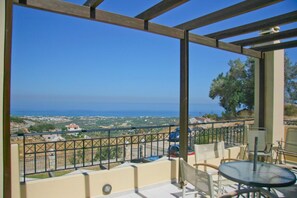 A balcony with a view of the sea and distant landscape.