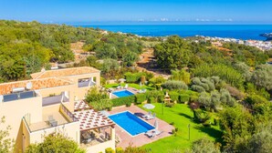 Zona residencial con una gran piscina, exuberante vegetación y vistas al mar.
