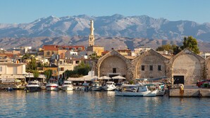 Un puerto con barcos, una mezquita con un minarete y montañas al fondo.