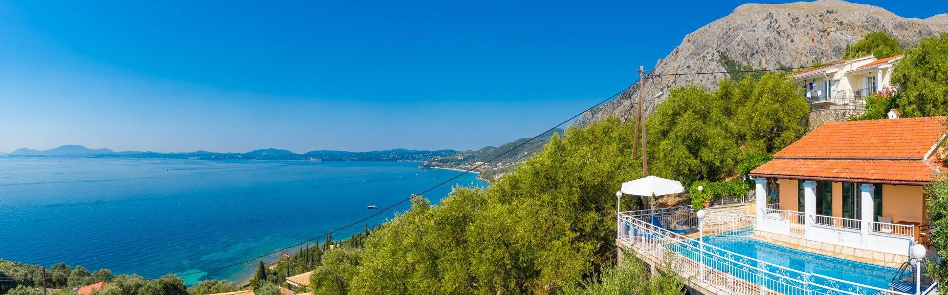 Une propriété située sur la côte, dotée d’une piscine, avec une chaîne de montagnes en arrière-plan et une vue dégagée sur la mer.
