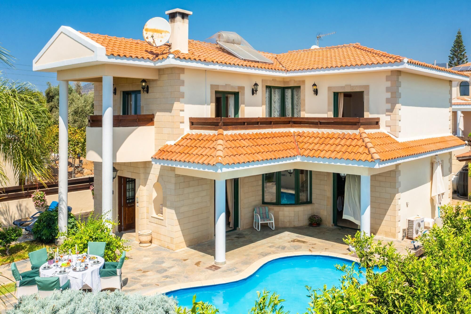 A two-story house with a swimming pool, outdoor seating, and a satellite dish.